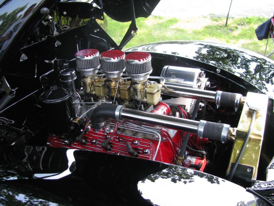 Hot rod engine with three red-topped carburetors and chrome intake pipes