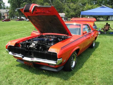 2003 Mercury Marauder - A classic orange Mercury Cougar is displayed with its hood open on a grassy field at an outdoor event.
