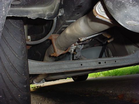 1999 Ford Taurus - Underside view showing exhaust pipe and suspension parts of a vehicle.