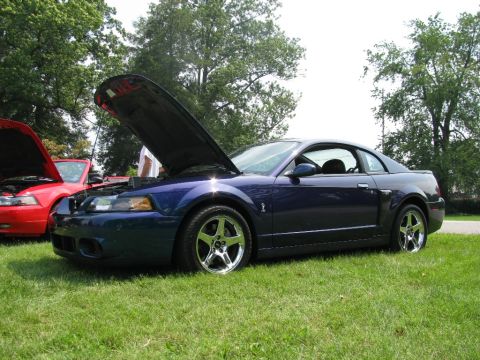 2003 Mercury Marauder - A dark blue Ford Mustang is parked on a grassy lawn with its hood open, alongside another car.