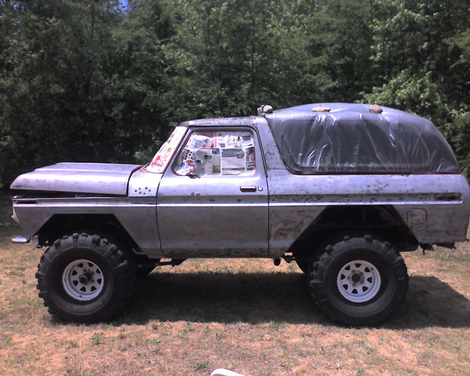 Side view of a 1979 Ford Bronco with large off-road tires and newspaper-covered windows