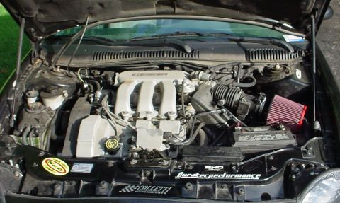 1999 Ford Taurus - The engine bay of a car is shown with aftermarket modifications including a red cone air filter.