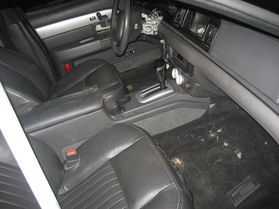 Black leather sedan interior with console shifter and dash partly disassembled