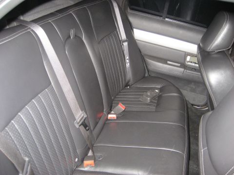 1999 Ford Crown Victoria - Rear bench seat of a sedan in black leather with perforated/pinstripe cloth-look inserts and contrast stitching, shot through the open rear…