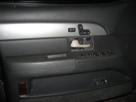 1999 Ford Crown Victoria - Interior shot of a gray driver's door panel with the interior door handle bezel removed, exposing the linkage and bare metal behind the tri…