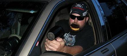 2000 Mercury Grand Marquis - Man inside a car holds a hairdryer to his face, wearing sunglasses and a baseball cap.