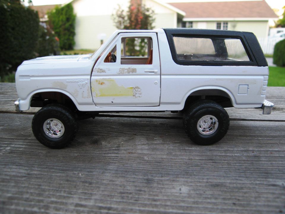 White diecast Ford Bronco model with black top sitting on a wooden surface