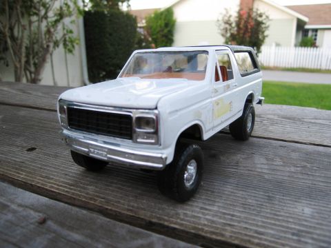 1986 Ford Bronco - A white diecast SUV sits on weathered wooden planks with a suburban background.