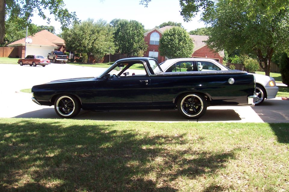 Dark blue Ford Ranchero in side profile parked on grass in a suburban yard