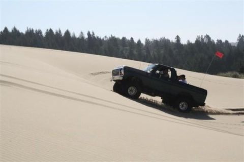 1979 Ford Bronco - A Ford Bronco navigates a sandy incline, kicking up dust as it goes.