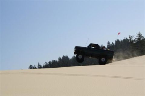1979 Ford Bronco - Ford Bronco airborne over a sand dune, kicking up dust.