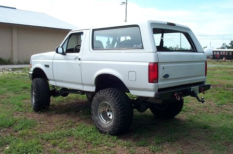 1995 Ford Bronco - This lifted 1995 Ford Bronco is shown from the rear three-quarter angle, parked on a grassy area.