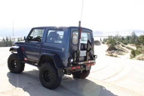 1979 Ford Bronco - This SUV is parked on sand dunes with a bridge visible in the distance.
