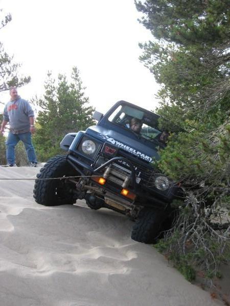 1979 Ford Bronco - A Suzuki Samurai navigates a sandy terrain, with a person observing the off-road adventure.