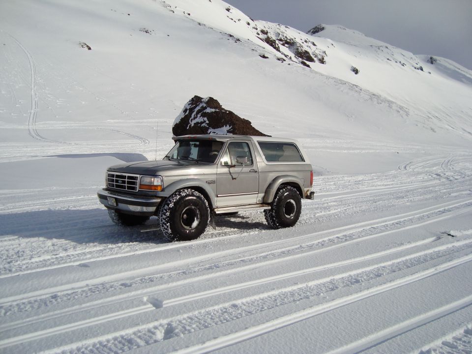 1992 Ford Bronco parked on a snowy track with mountains in background