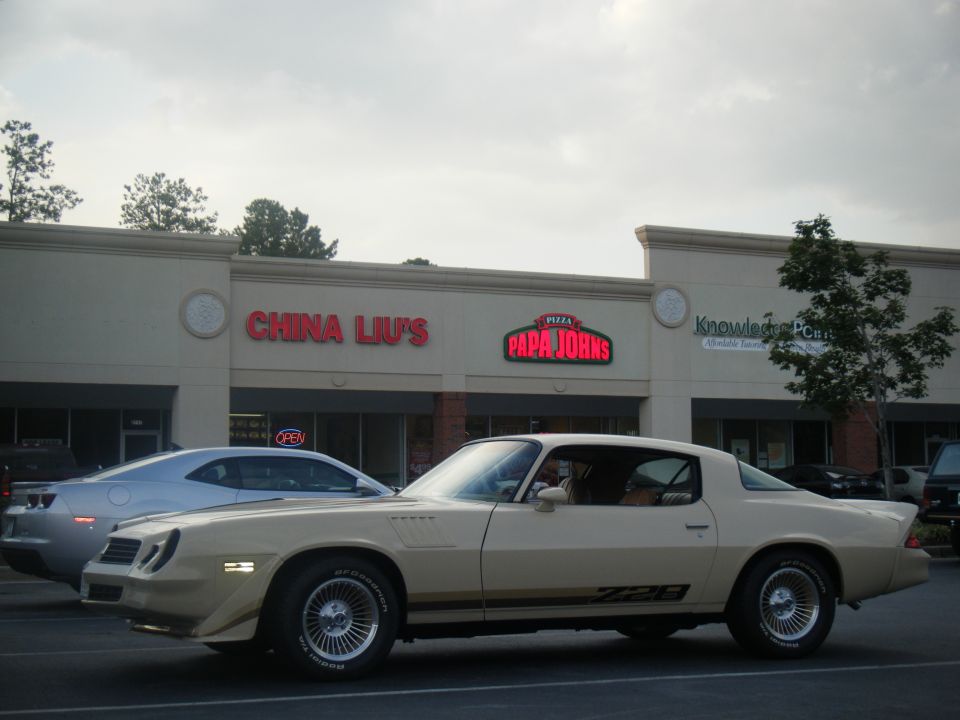 Tan Chevrolet Camaro Z28 parked in front of strip mall stores