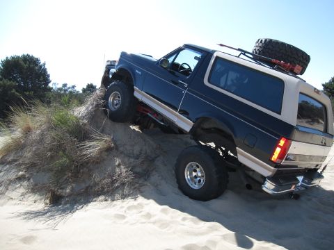 1996 Ford Bronco - Ford Bronco navigating a sandy incline with off-road modifications.