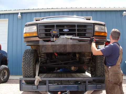 1993 Ford Bronco - Ford Bronco on a trailer, being worked on. A man is holding a metal bar near the custom bumper.