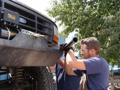 1993 Ford Bronco - Two men work on installing a custom bumper on a Ford truck, with a winch mounted on the front.