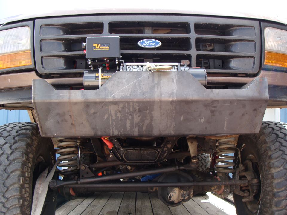 Brown Ford truck front end with custom bumper and winch. Visible grille and headlights