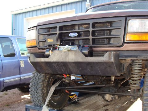 1993 Ford Bronco - The front of a brown 1993 Ford Bronco shows a custom bumper with a winch mounted behind it, alongside the Ford grille badge.