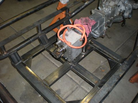 Suzuki Samurai - Overhead shot of a bare tube frame under construction in a garage, with a fabricated square-body transfer case and a cast transmission hous…
