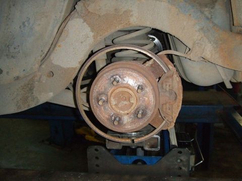 2001 Ford F-150 - Close-up view of a vehicle's rear brake rotor and caliper, showing signs of wear and rust.