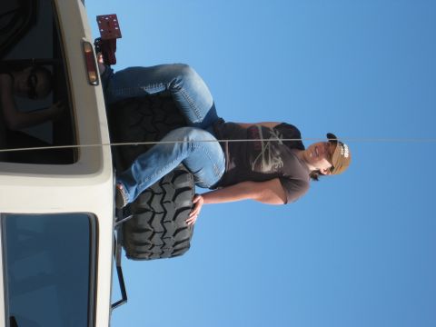 1979 Ford Bronco - A person rests on a spare tire mounted externally on a vehicle against a clear blue sky.