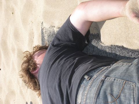 1979 Ford Bronco - A person rests on a sandy beach, partially covered by sand.