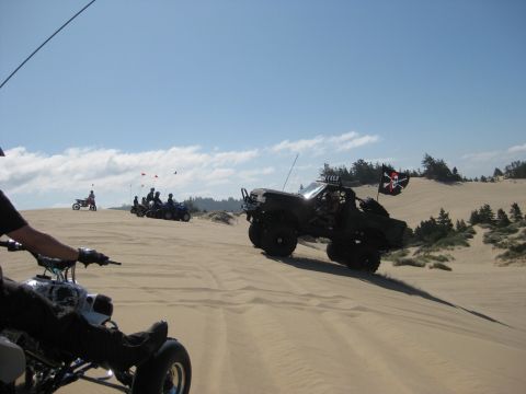 1979 Ford Bronco - Dune scene shot from the seat of a quad, showing a dark open-top full-size 4x4 truck climbing a sand ridge on oversized tires with a roll b…