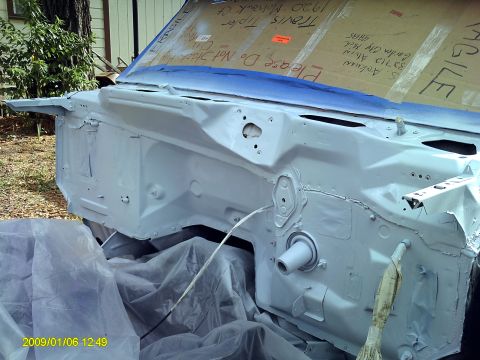 1992 Ford Bronco - The engine bay of a vehicle is prepped for paint, with protective coverings and tape in place.