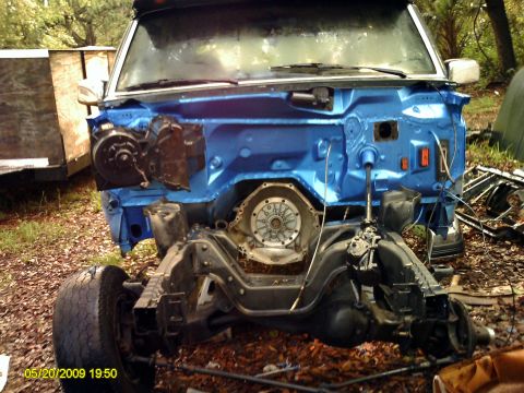 1992 Ford Bronco - The front end of a vehicle is disassembled, revealing the transmission and a freshly painted blue firewall.