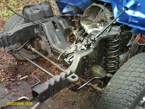 1992 Ford Bronco - The front frame and suspension of a blue vehicle are visible, with the chassis and springs exposed.