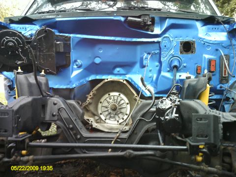 1992 Ford Bronco - The engine bay and chassis of a vehicle are shown, with the transmission housing exposed and painted blue.