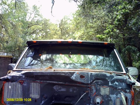 1992 Ford Bronco - The front end of a heavily damaged 1980s Ford Bronco is visible, with its grille and hood removed.