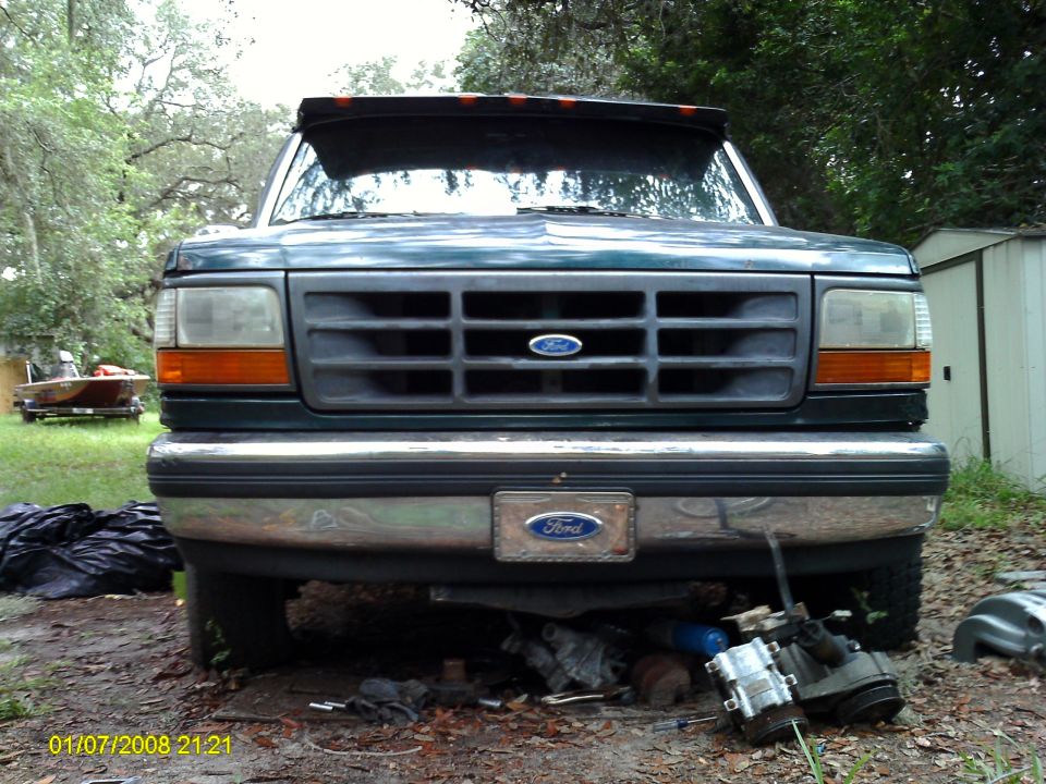 Front view of a green Ford F-Series truck, possibly a 1992 model. Parts are visible underneath