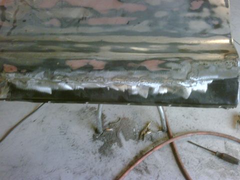 1979 Ford F-250 - Close-up of a truck door bottom undergoing repair with visible welding and body filler.