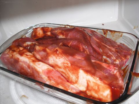 1991 Ford Bronco - Several racks of raw ribs are covered in a red sauce and placed in a clear glass baking dish.
