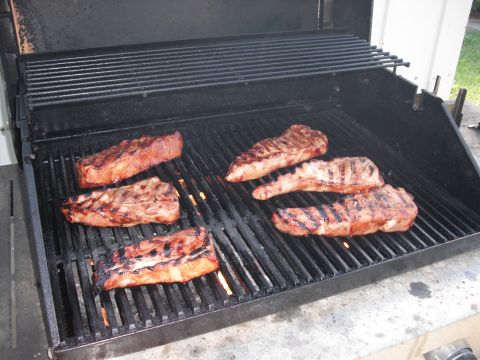 1991 Ford Bronco - Several steaks are being grilled, with visible flames underneath the grates.