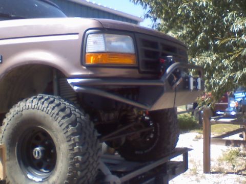 1993 Ford Bronco - Front corner of a brown Ford truck with an aftermarket bumper and off-road tires is shown.