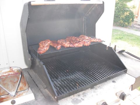 1991 Ford Bronco - Steaks are cooking on a gas grill outdoors.