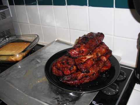 1991 Ford Bronco - A stack of barbecued ribs sits on a plate beside a pan of cornbread on a kitchen stove.