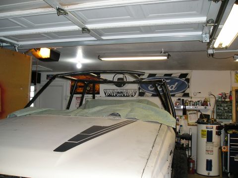 1986 Toyota Hilux - Vehicle interior with roll cage structure visible, covered with a tarp in a garage setting.