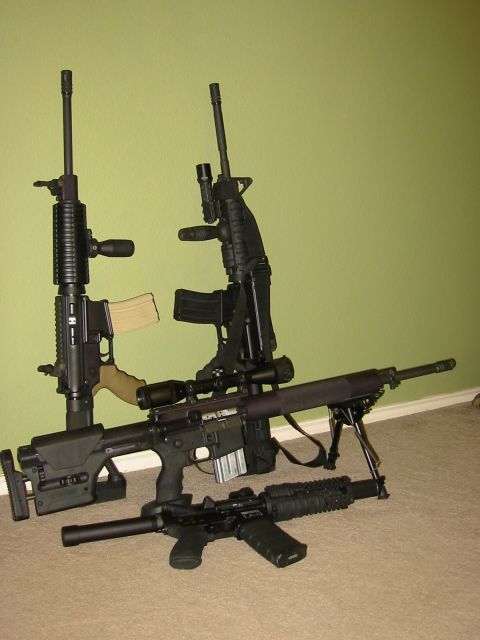 1996 Ford Bronco - An assortment of firearms, including rifles and a sniper rifle with a bipod, are displayed against a light green wall.