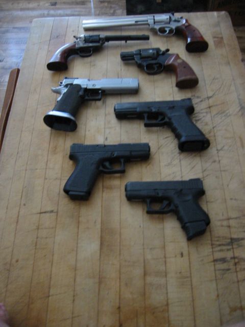 1996 Ford Bronco - Various handguns are displayed on a wooden surface, with a website watermark at the bottom.