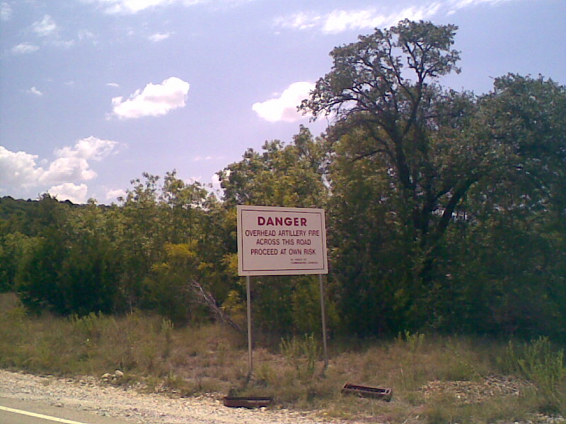 Danger sign warning of overhead artillery fire across the road