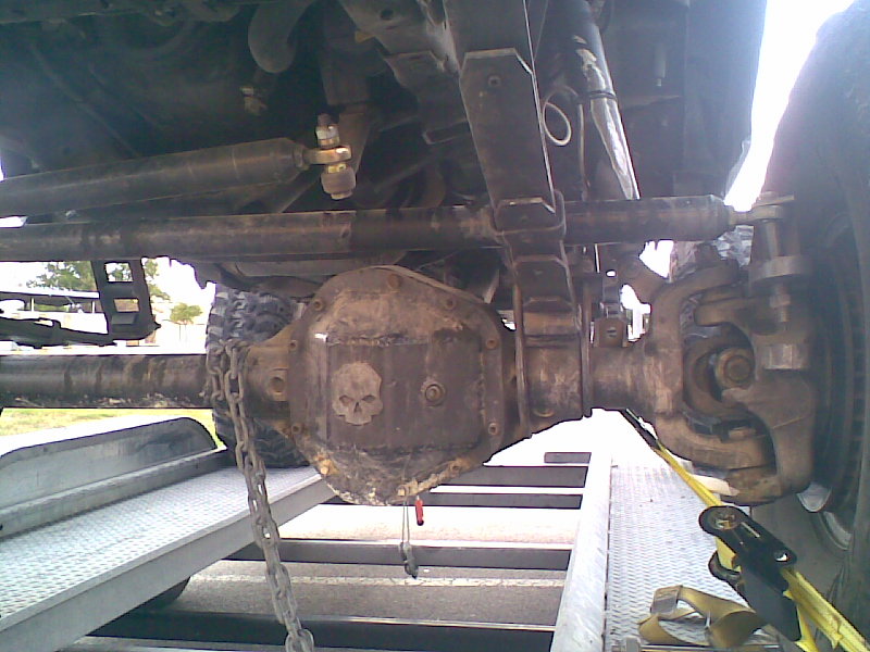 Close-up of a vehicle's rear differential with a skull sticker, leaf springs, and shock absorber