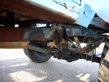 1973 Ford Bronco - Close-up view of the undercarriage and suspension of a weathered vehicle.