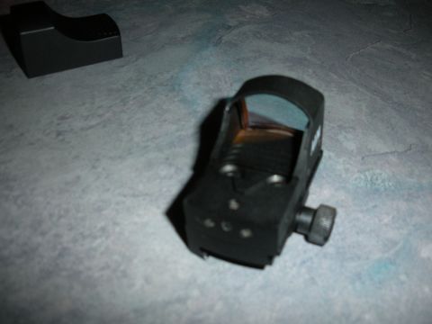 1996 Ford Bronco - A black red dot sight is shown with its mounting base on a textured surface.