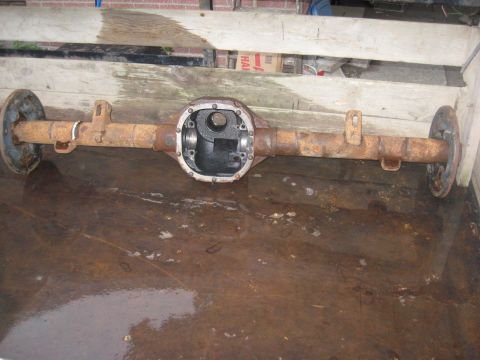 1995 Ford Bronco - A rusty Ford 8.8 inch rear axle assembly is shown from the side, with brake drums attached.